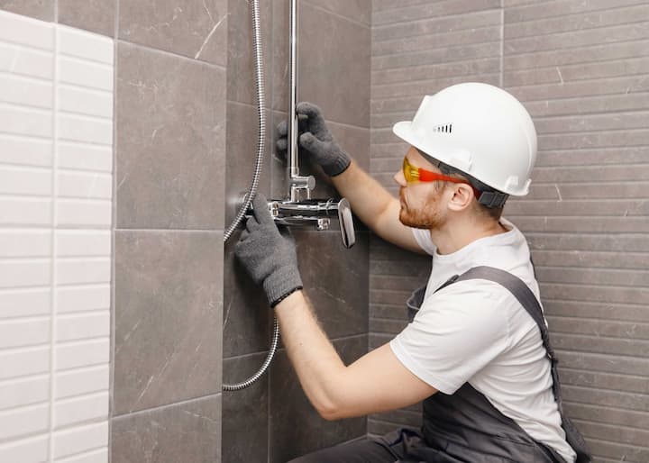 A professional shower installer adds fixtures to a new shower in a New Orleans, LA bathroom.